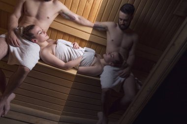 Genç çift sauna seansının tadını çıkarıyor ve rahatlıyor.