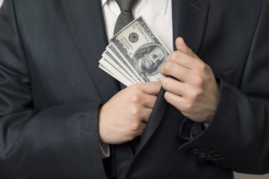 Ceketinin cebine para koyan takım elbiseli bir adamın ayrıntıları. Seçici odak