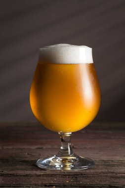 Kırsal ahşap bir masada bir kase fıstıkla bir bardak soğuk soluk bira. Köpüğe odaklan.