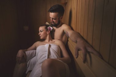 Genç çift sauna seansının tadını çıkarıyor ve rahatlıyor.
