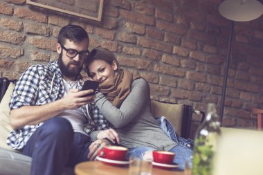 Genç bir çift bir kafede oturuyor, sabah kahvelerini içiyor, internette akıllı bir telefonla sörf yapıyor ve birlikte vakit geçiriyorlar. Kıza odaklan.