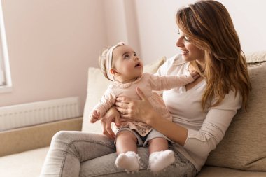 Genç bir anne kucağında bebeğini kucağında tutuyor ve anneliğin tadını çıkarıyor. Bebeğe odaklan.