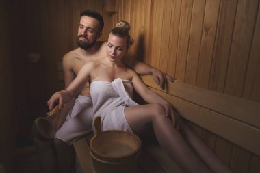 Genç çift sauna seansının tadını çıkarıyor ve rahatlıyor.