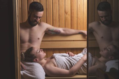 Genç çift sauna seansının tadını çıkarıyor ve rahatlıyor.