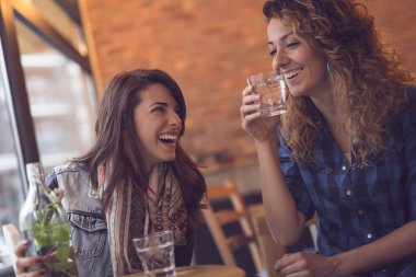 İki arkadaş bir kafede oturuyor, boş zamanlarının tadını çıkarıyor ve eğleniyorlar. Soldaki kıza odaklan.