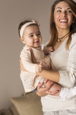 Genç bir anne, bebeğini kucağına alıp kucaklarken birlikte vakit geçiriyorlar. Bebeğe odaklan.