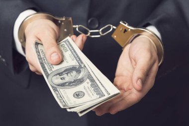 Kelepçeli takım elbiseli bir iş adamı, tutuklanmış, serbest bırakılması için rüşvet teklif ediyor. Seçici odak