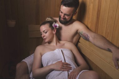 Genç çift sauna seansının tadını çıkarıyor ve rahatlıyor.