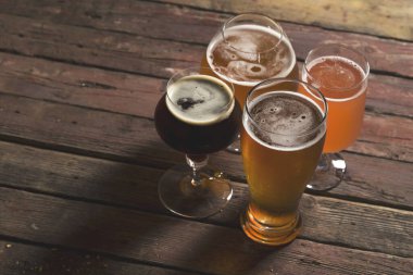 Soluk, koyu, filtresiz, soluk ve kırmızı meyve birası kırsal bir masada dört farklı bira bardağında. Seçici odak