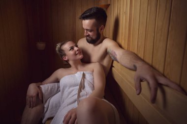 Genç çift sauna seansının tadını çıkarıyor ve rahatlıyor.