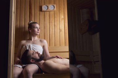 Genç çift sauna seansının tadını çıkarıyor ve rahatlıyor. Kıza odaklan.