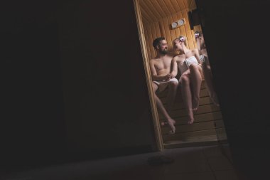 Genç çift sauna seansının tadını çıkarıyor ve rahatlıyor.
