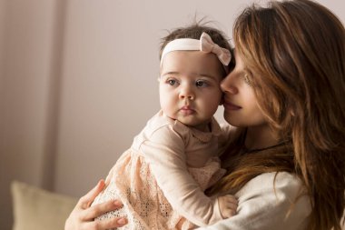 Genç bir anne bebeğini kucağına alıp kucaklıyor. Bebeğe odaklan.