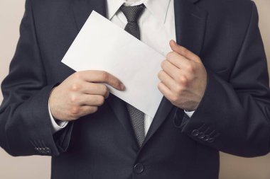 Ceketinin cebine para koyan takım elbiseli bir adamın ayrıntıları. Seçici odak
