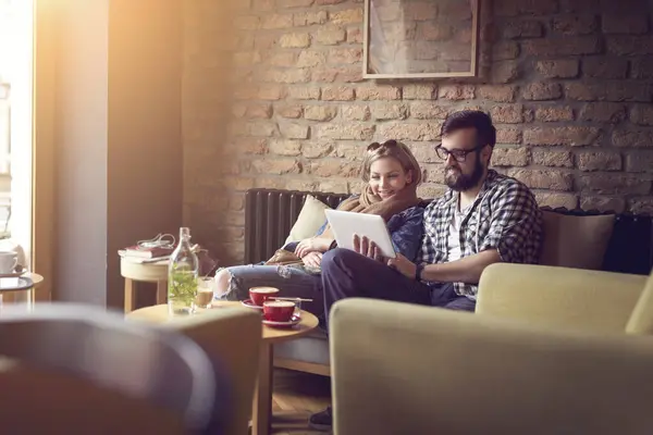 这对年轻夫妇坐在咖啡店里 喝着早茶 在平板电脑上冲浪 享受着他们在一起的时光 — 图库照片
