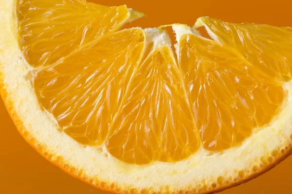 Close up of an orange slice isolated on orange background