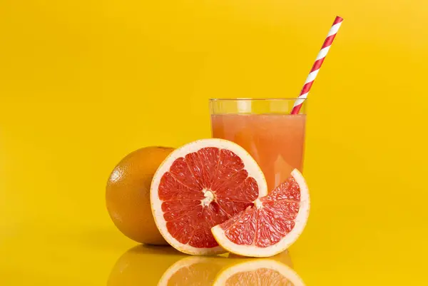 全体の赤いグレープフルーツ クロスセクション グレープフルーツジュースの隣に置かれたスライスは オレンジ色の背景に隔離されたストローを飲んでいます フォーカススタック画像 — ストック写真