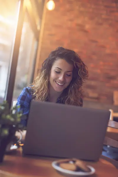 カフェに座り コーヒーを飲み ラップトップコンピュータで作業する若い女性 — ストック写真