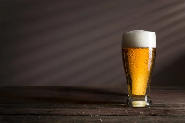 素朴な木のテーブルの上に冷たい淡いビールのガラス — ストック写真