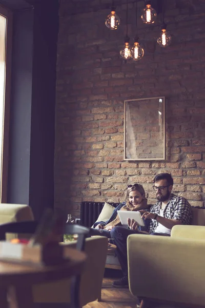 カフェに座り 朝のコーヒーを飲み タブレットコンピュータでウェブをサーフィンし 一緒に時間を楽しんでいる若いカップル — ストック写真