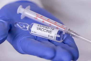 Bir covid-19 aşı şişesi ve şırınga tutan bir sağlık uzmanı; elinde yeni Corronavirus aşısı tutan bir doktor