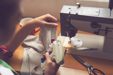 Terzi yeni yapılmış bir tişörte etiket yapıştırıyor. Etiket tabancası var. Kırmızı düğmeye seçmeli odak