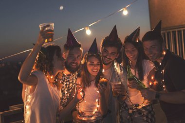 Bir grup genç arkadaş binanın çatısında doğum günü partisi veriyor, şarkı söylüyor ve mum üflüyorlar. Doğum günü kızına odaklan.