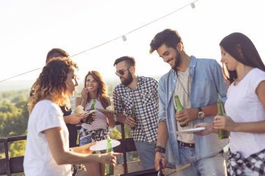 Bir grup genç arkadaş çatıdaki partide eğleniyor, barbekü yapıyor, bira içiyor ve sıcak yaz günlerinin tadını çıkarıyor. Ortadaki kıza odaklan.