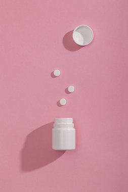 Pembe arka planda izole edilmiş ve fotokopi alanı olan bir ilaç şişesinin üst görüntüsü; 