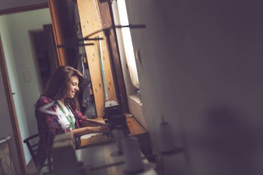 Terzi dikiş makinesinde oturup atölyede dikiş dikiyor.