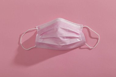 Pembe renkli arka planda izole edilmiş pembe cerrahi yüz koruma maskesinin üst görüntüsü. Covid-19 salgınına karşı korunma ekipmanının bir parçası olarak tıbbi maske