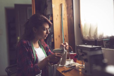 Terzi yeni yapılmış bir tişörte etiket yapıştırıyor..