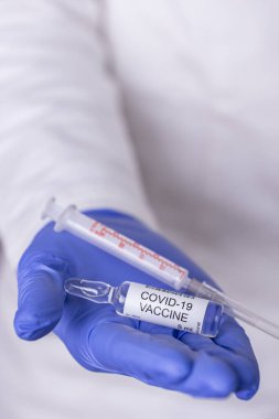 Bir covid-19 aşı şişesi ve şırınga tutan bir sağlık uzmanı; elinde yeni Corronavirus aşısı tutan bir doktor