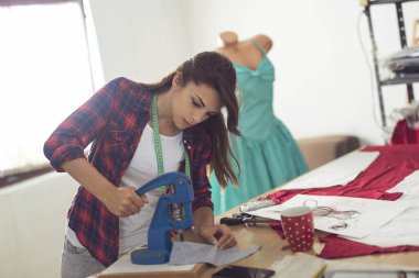 Atölyesinde çalışan genç terzi kumaşa düğme takıyor.