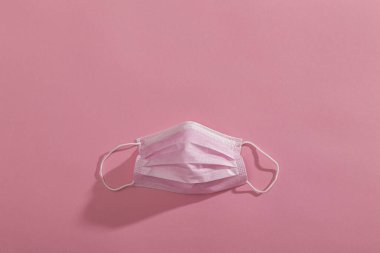 Pembe cerrahi yüz koruma maskesinin üst görüntüsü pembe arka planda izole edilmiş. Covid-19 virüs salgınına karşı korunma ekipmanının bir parçası olarak tıbbi maske