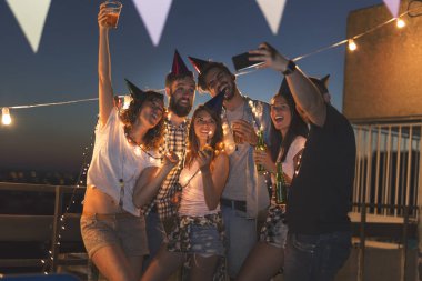 Bir doğum günü partisinde selfie çeken bir grup genç. Seçici odak