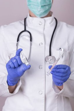 Bağışıklık bilimci elinde bir covid-19 aşı şişesi ve şırınga tutuyor; doktor elinde yeni Corronavirus aşısı tutuyor.