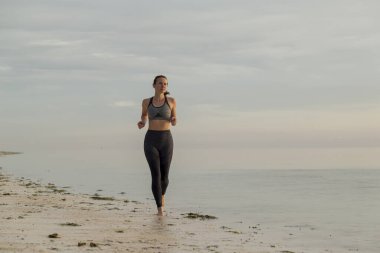 Genç bir kadın sabahları sahilde çalışıyor, sahil boyunca koşuyor.