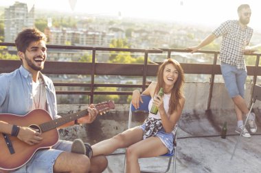 Genç arkadaşlar gitar çalıyor, şarkı söylüyor ve çatıdaki bir partide eğleniyorlar, sıcak yaz günlerinin tadını çıkarıyorlar. Kıza odaklan.
