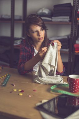 Genç terzi tamirat yapıyor, gömleğinin düğmelerini elle dikiyor.