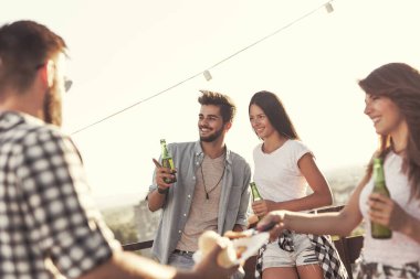 Bir grup genç arkadaş çatıdaki partide eğleniyor, barbekü yapıyor ve sıcak yaz günlerinin tadını çıkarıyorlar. Arka plandaki kıza odaklan.