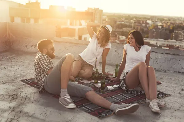 Young people chilling out and partying on a building rooftop. Focus on the girl in the middle