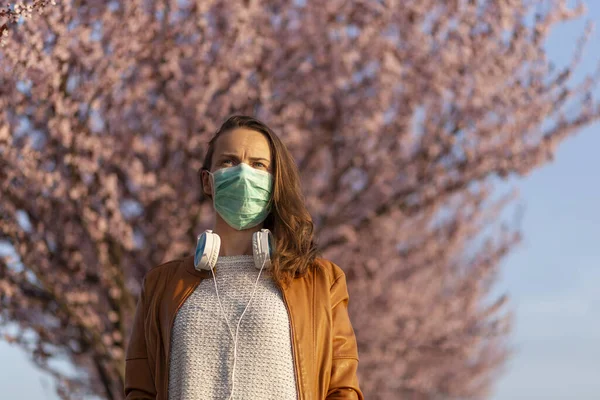 Woman wearing medical face protection mask while taking a walk outdoors during covid-19 pandemic