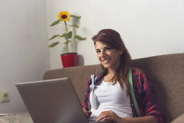 ソファーに座ってラップトップコンピュータで働く若い女性 — ストック写真