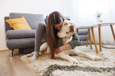 Evcil köpeğine sarılıp sarmaş dolaş güzel bir genç kadın.