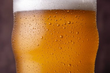 Camın yüzeyinde çiğ ve yoğunlaştırılmış su damlacıklarıyla soğuk bira bardağını kapat.