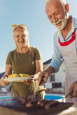 Son sınıf çiftimiz arka bahçede barbekü partisi veriyor, et ve mısır pişiriyor ve boş zamanlarında dışarıda eğleniyorlar.