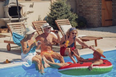 Bir grup neşeli son sınıf öğrencisi yaz tatilinde kokteyl içip bira içerken yüzme havuzunda güneşleniyor ve dinleniyorlar. 