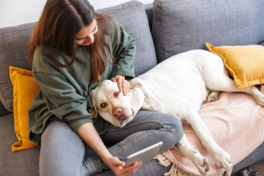 Güzel genç bir kadın köpeğiyle selfie çekerken evde dinlenip eğlenirken eğleniyor.