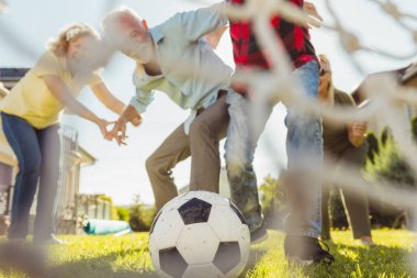 Bir grup aktif son sınıf öğrencisi arka bahçedeki çimlerde futbol oynayarak eğleniyor güneşli bir yaz gününün tadını çıkarıyor ve gol attıktan sonra kutlama yapıyorlar.